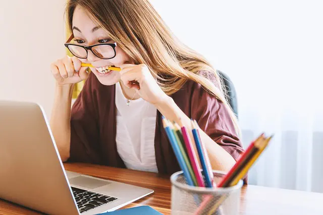 jeune femme étudiant avec ordinateur portable et crayons de couleur sur son bureau
