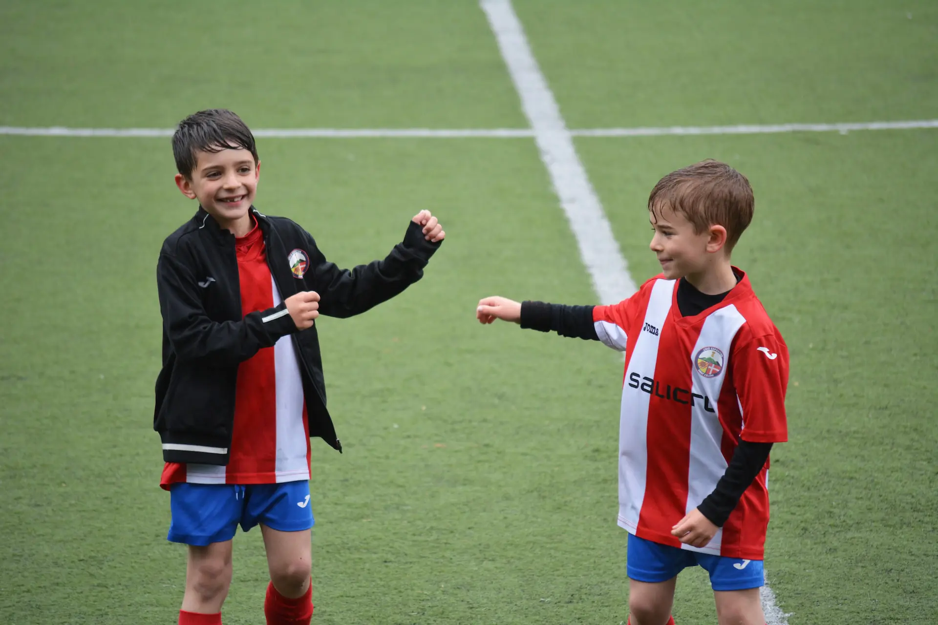 deux jeunes enfants en tenue de soccer rouge et blanche sur un terrain