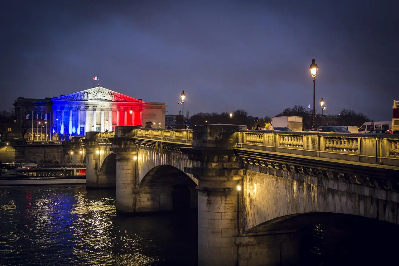 palais bourbon illuminé aux couleurs françaises avec pont et seine à paris la nuit