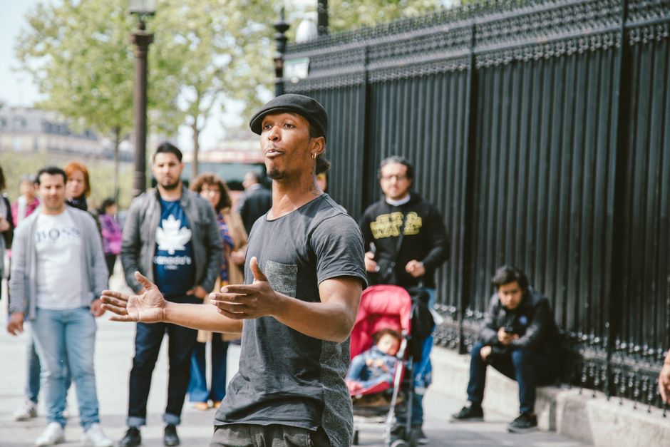 Street performer captivates an audience with lively dance moves in an urban outdoor setting.